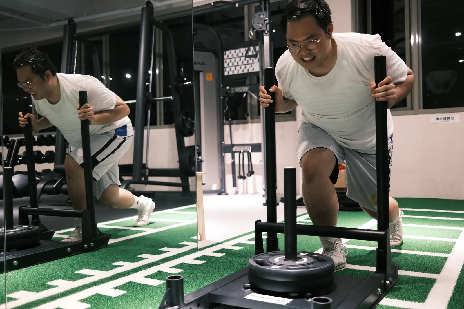 TIDAL Fitness 會員在草皮跑道上進行雪橇推行訓練